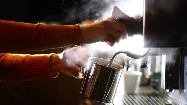 Color footage of a barista pouring hot water in a metallic mug.