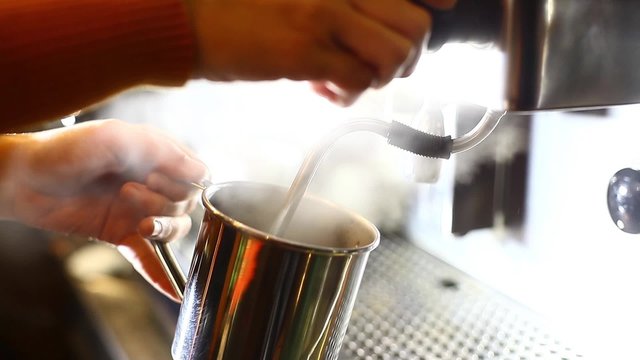 Color footage of a barista pouring hot water in a metallic mug.