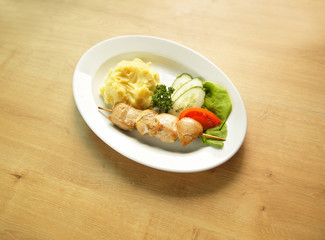 .kebab with side dish and vegetables on white plate 
