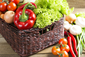 Wicker basket with fruits and vegetables on the table