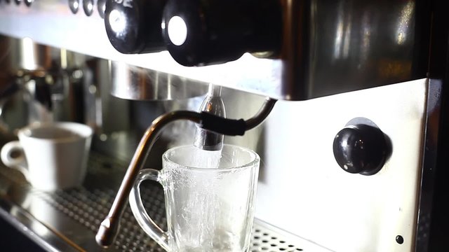 Panning footage of a barista pouring hot water in a glass.
