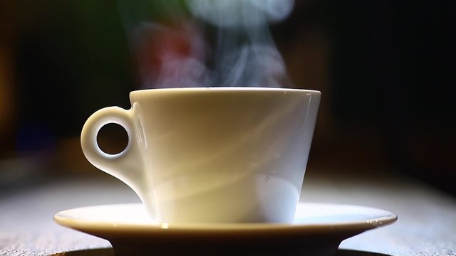 Color footage of a coffee mug put on a plate, with steam.