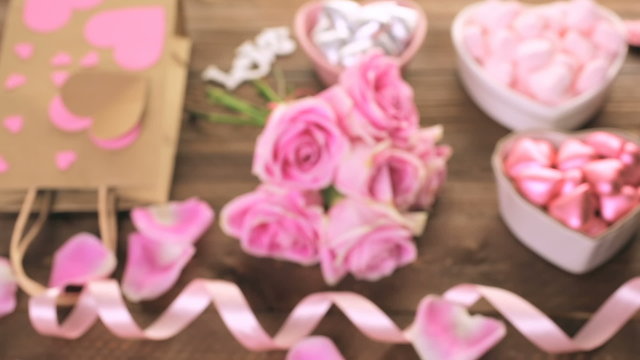 Pink roses with chocolates on rustic wood table