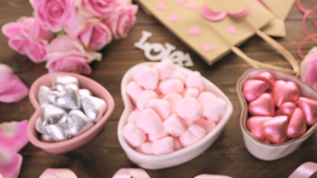 Pink roses with chocolates on rustic wood table