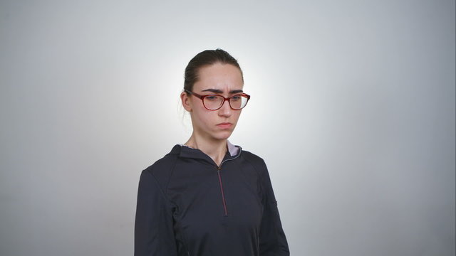 Closeup portrait angry, arrogant, sly, scheming young woman in glasses plotting something isolated on gray background. Negative human emotions, facial expressions, feelings, attitude, reaction. RAW