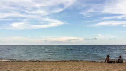 Two men sitting and talking on ocean sandy beach