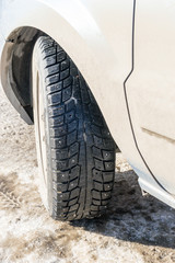Fototapeta na wymiar Winter Tire on a Grey Car in Sunlight