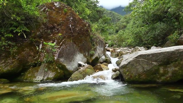 Experience the breathtaking beauty of the Ruta de las Cascadas in Baños,Ecuador,as you witness the mesmerizing river flowing through the enchanting rainforest.