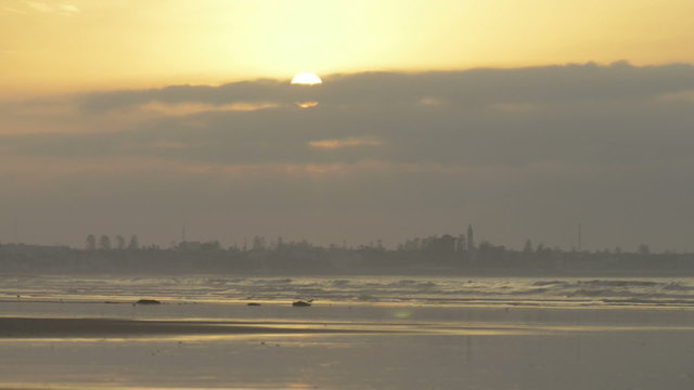 Beautiful sunset at beach, light beam shining through cloudscape