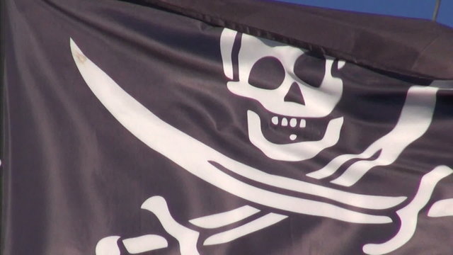 Black pirate flag waving on ship mast on sunny day