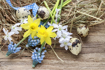 Easter decorations with springtime flowers, quail eggs and hay