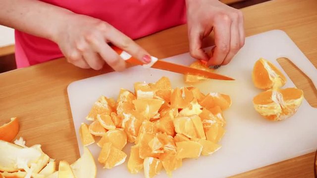 Woman housewife in kitchen cutting orange fruits 4K