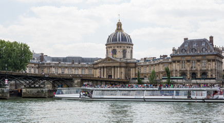 Tourist boat cruise on River Seine, Paris, near Pont de Arts and historical buildings