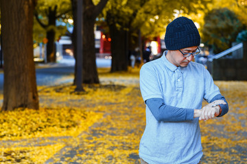 A Man in a Polo T-shirt on Sidewalk of a Street with Ginkgo Trees in Autumn