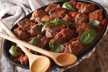 Spicy beef with sauce and basil close up in a dish. horizontal