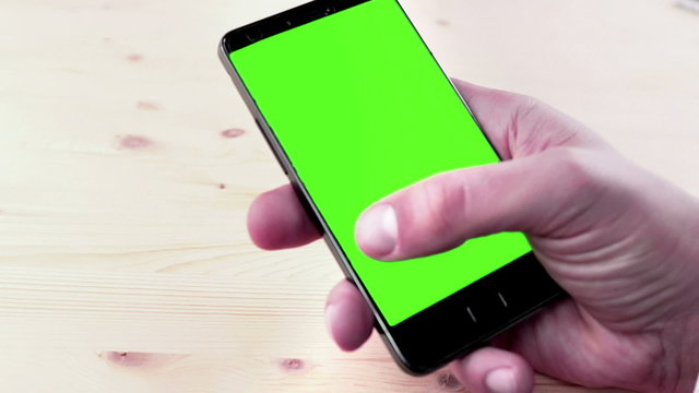 man hands using a smart phone for write text messaging with chroma key, green screen on wood table, communication with smartphone technology concept