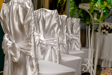Fototapeta na wymiar Chairs in white covers with a white ribbon