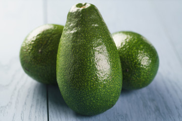 whole ripe green avocados on wood table, selective focus