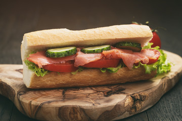 sandwich with salmon and vegetables on wood table, vintage toned