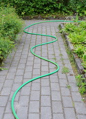 Water hose lying on the road in the garden