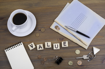 Coffe, pen, money and blocknot on a desk and word Value