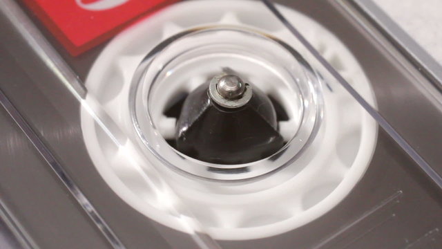 Close up of the spindle of an audio music cassette tape playing in a recorder.