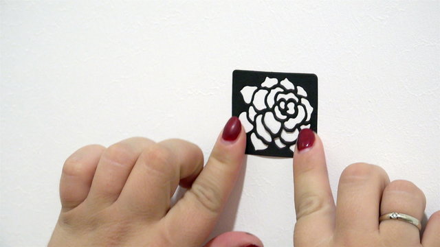 female hand sticks a black screen in the form of a rose on a white base