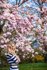 girl stands near a flowering magnolia tree