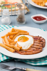 English breakfast with grilled ham, fried egg and french fries.