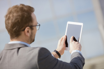 Manager using digital tablet device in front of the business building   