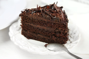 Sliced chocolate cake on wooden table, on light background