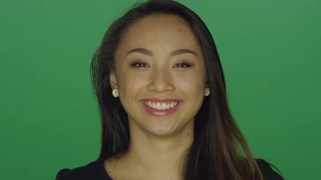 Beautiful young woman laughing and smiling, on a green screen studio background 