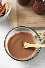 Melted chocolate on glass bowl, on wooden background