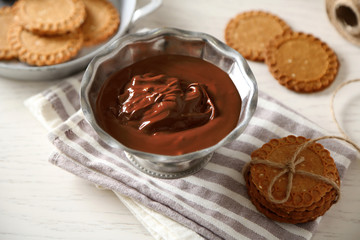 Melted chocolate in bowl, on wooden background