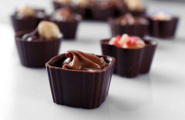 Delicious chocolate candies on white background, close up