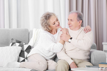 Happy mature couple sitting together on a sofa at home