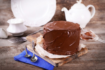 Chocolate cake with two spoons and blue tablecloth on a wooden boards background
