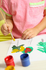 Child drawing tree with bright paints on paper, closeup