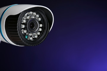 Security CCTV camera on blue background, closeup