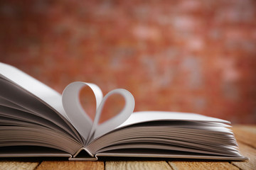 Sheets of book curved into heart shape on unfocused background