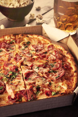 Tasty pizza in carton and glass of beer are on wooden table, close up