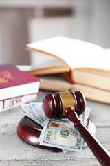 Gavel with books and money on wooden table closeup