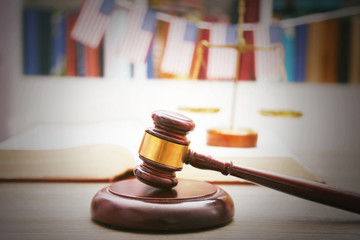 Gavel with justice scales and open book on wooden table, close up