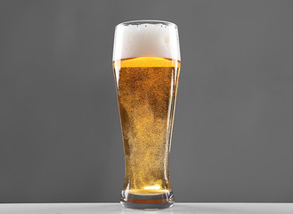 Glass of lager beer on grey background