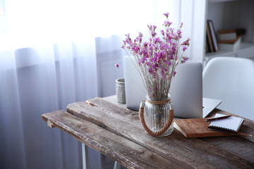 Modern interior. Comfortable workplace. Wooden table with beautiful bouquet of flowers and laptop...