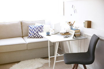 Modern interior. Comfortable workplace. Table with laptop and cup of coffee on it