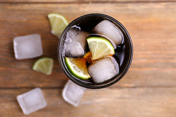 Cocktail with lime slices and ice blocks on wooden table, top view
