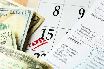 A red tax mark in the calendar, tax form with dollar bills, close up