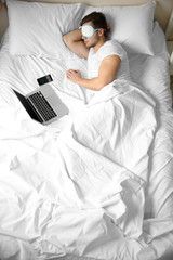 Young man sleeping with blindfold in bed at home