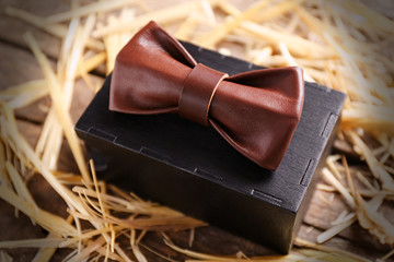 Brown leather bow tie with special packaging on a thatch, close up